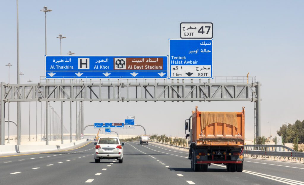 a truck driving down a highway with a sign above it.